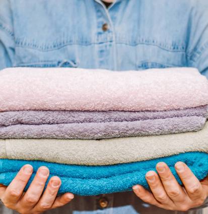 Man is organizing and cleaning the house. Stack of clean terry towels in hand. Storage and housekeeping concept.